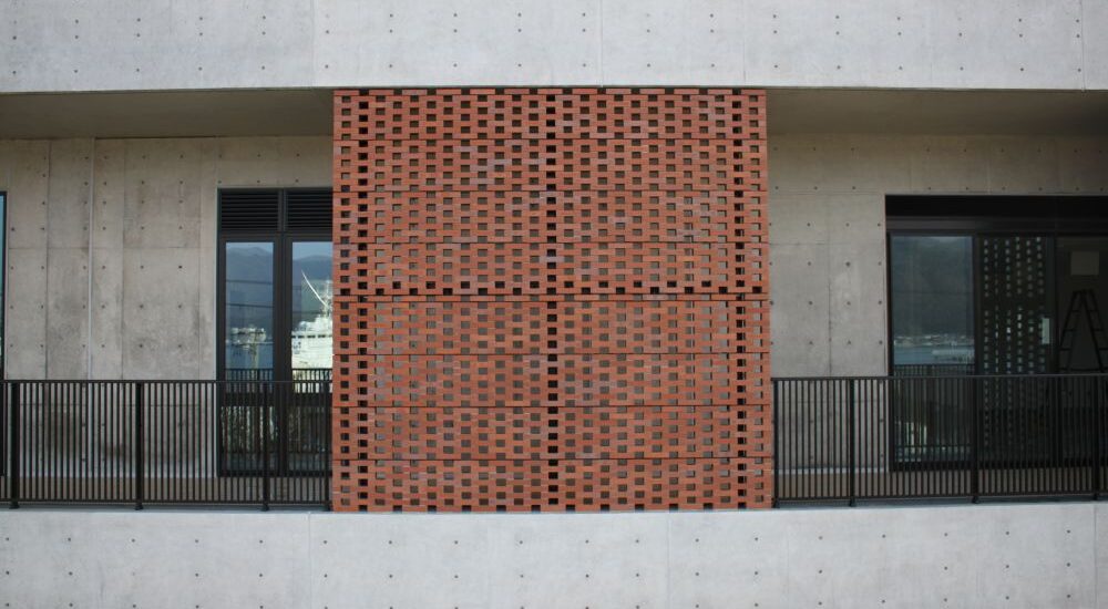 空中から撮影した打ち放しコンクリート外壁の施工事例。化粧補修により色調整と質感を整え、建築全体との調和を実現した外観仕上げ。