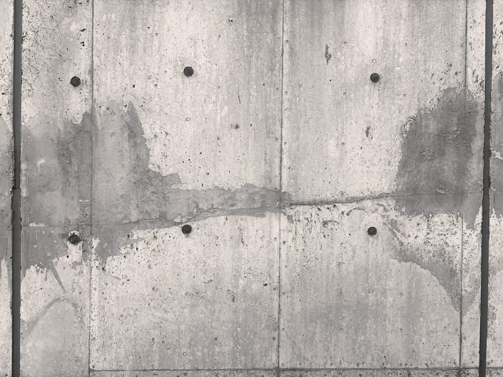 劣化と色ムラが発生した打ち放しコンクリート外壁の補修前状況。左官補修が必要な施工事例。Exposed concrete surface before plaster restoration.